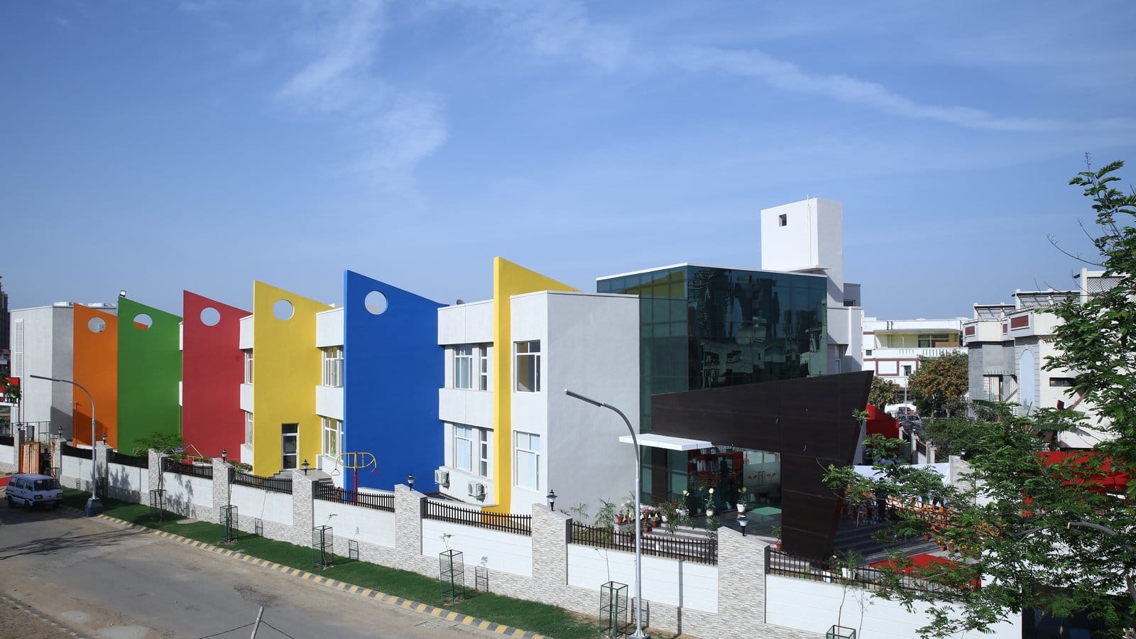 The primary wing of The HDFC School (now The Knowledge Habitat) in Block C, Sushant Lok 3, Sector 57, Gurgaon: red, blue, yellow and green façades behind a boundary wall on a colony road