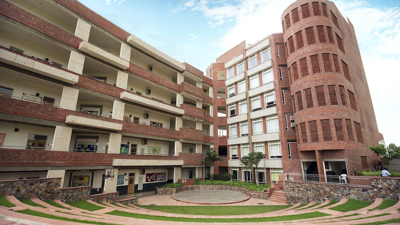 The HDFC School senior wing in Sector 57, Sushant Lok 3: red-brick classroom blocks and a round tower behind a grassed amphitheatre