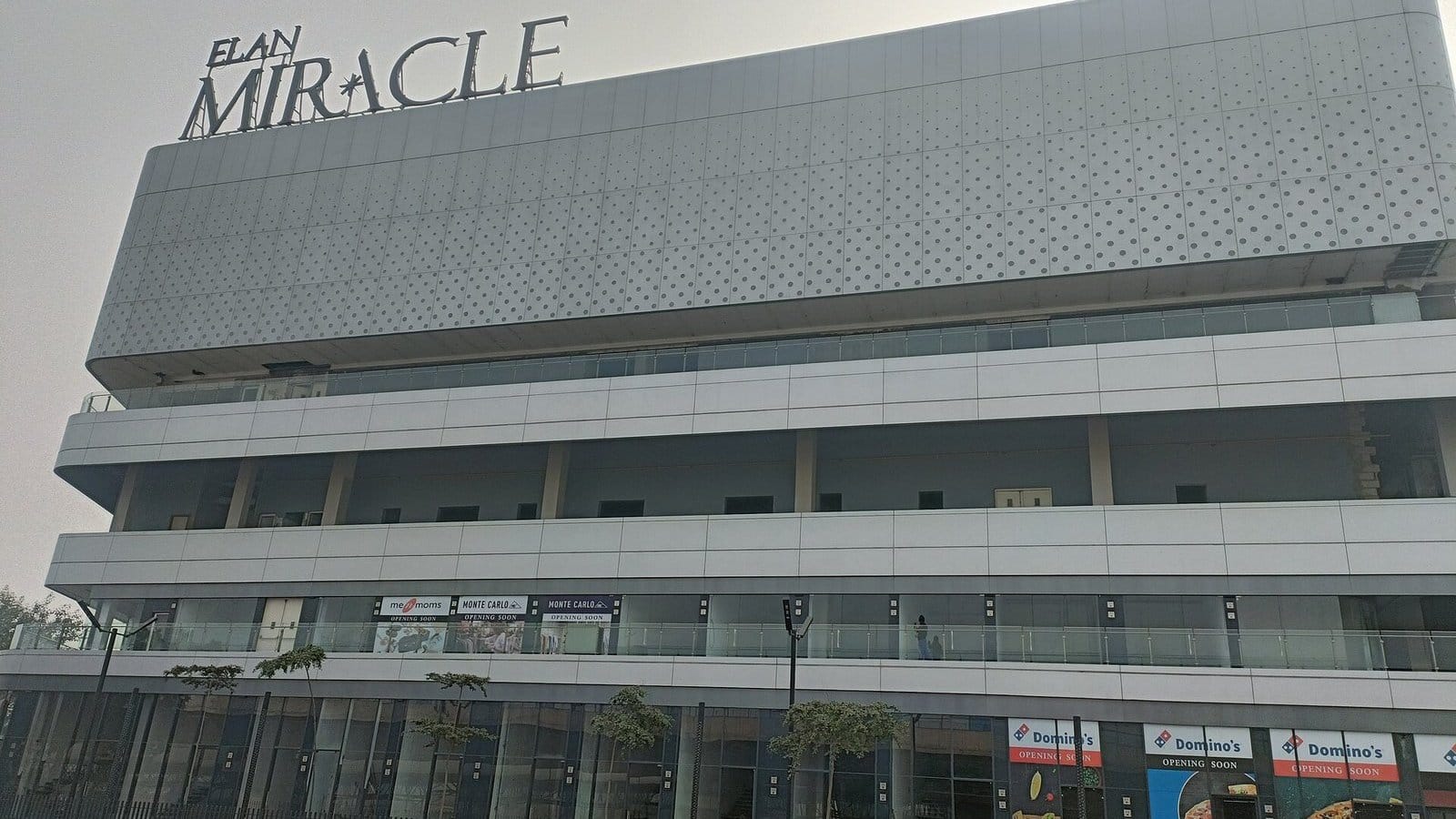 The Elan Miracle retail building in Sector 84, Gurugram: a grey perforated facade with the ELAN MIRACLE sign on the roof and shopfronts at street level
