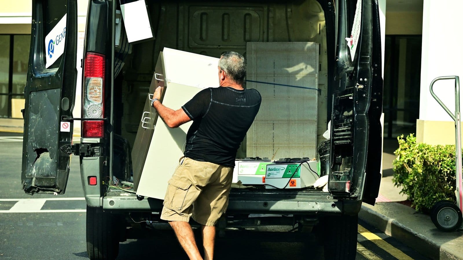 A man loading a white cabinet into the back of a van