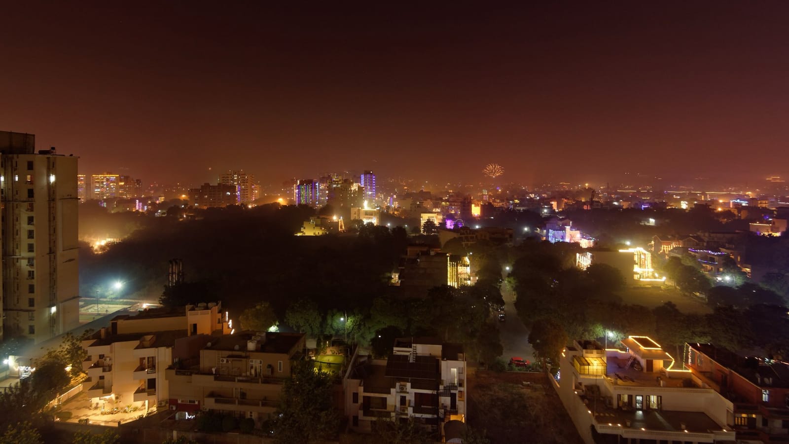 Sector 47, Gurgaon, at night during Diwali, seen from a high floor: lit plotted houses in front, an apartment tower on the left and city lights behind
