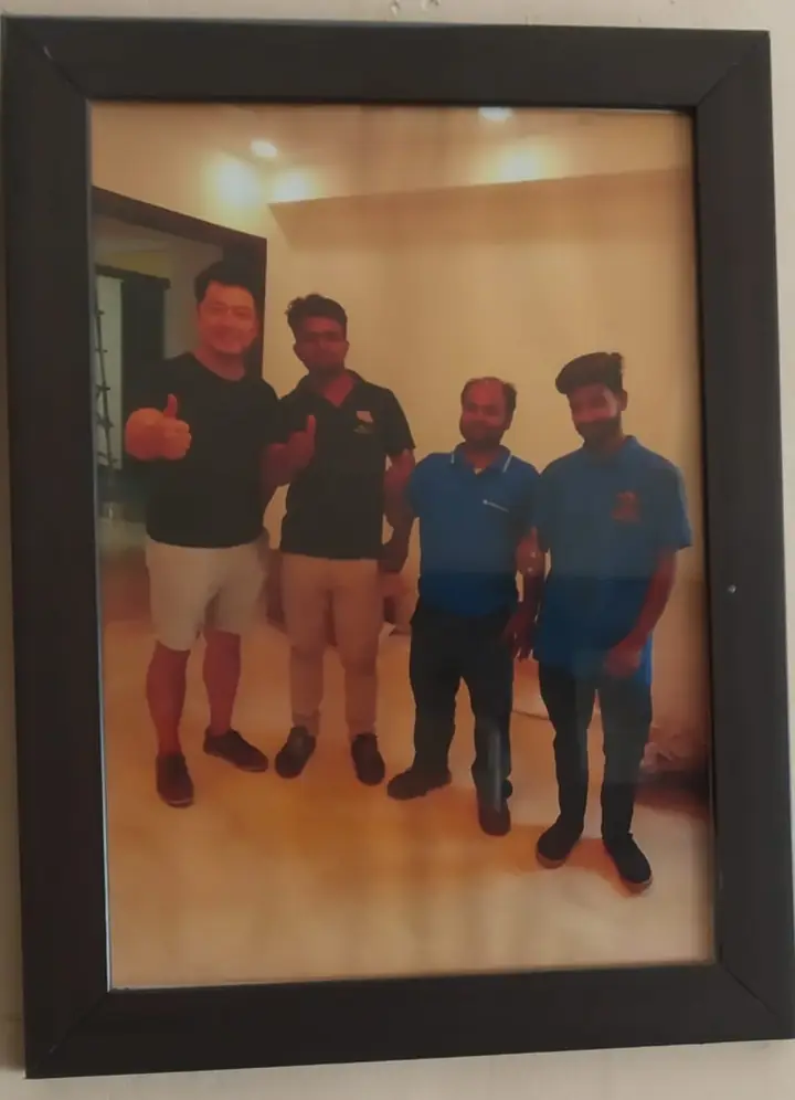 Framed photo of three crew members and a customer giving a thumbs up in an empty flat
