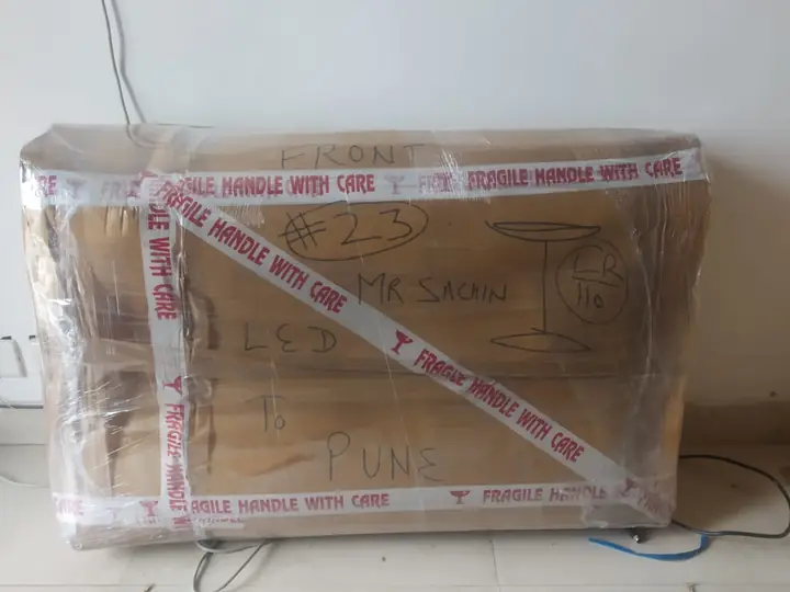 LED TV carton marked FRONT and numbered 23, with a hand-drawn glass symbol, FRAGILE tape on every edge and “to Pune” written on it