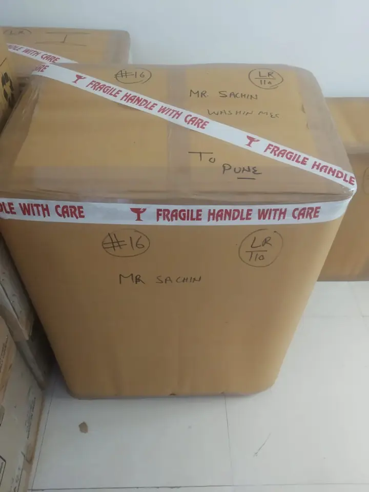 Washing machine packed in a carton numbered 16, taped FRAGILE and labelled “washing machine, to Pune” in marker