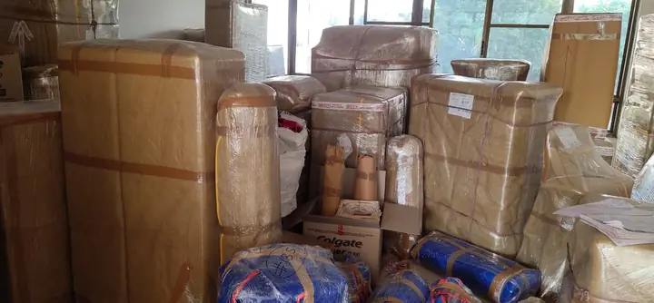 A room filled with film-wrapped furniture, taped cartons and bedding bundled in blue sheets, waiting to be loaded