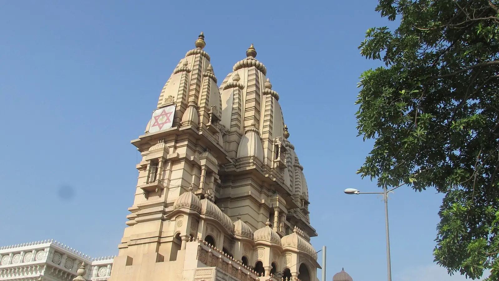 Illustration: the carved sandstone spires of Chhatarpur Mandir against a clear blue sky.