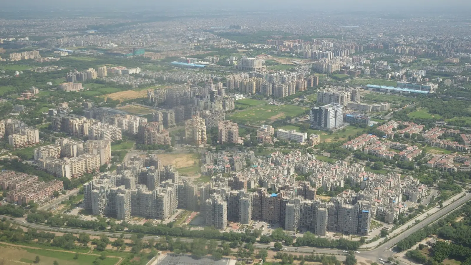Illustration: aerial view over Dwarka's DDA and group-housing apartment blocks and wide sector roads. Used for several pages because it is generic Dwarka sector housing; no sector-specific photo exists for Sectors 6, 7, 19, 22 or 23.